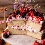 Split open berries and cream cake on a platter.