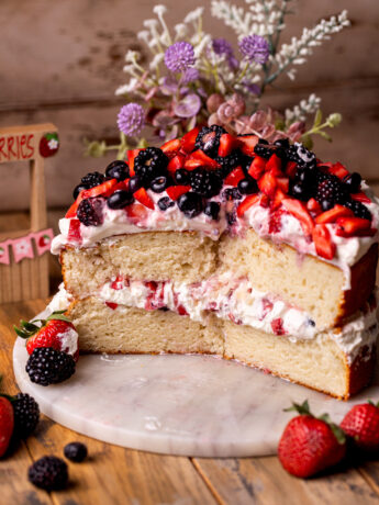 Split open berries and cream cake on a platter.