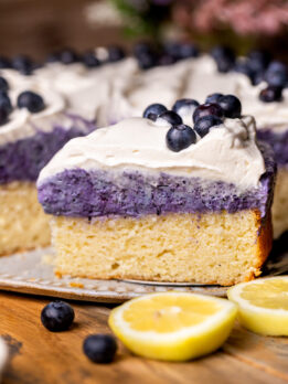 Slice of the lemon blueberry mousse cake by the whole cake.