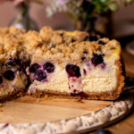 Side view of a slice of blueberry crumble cheesecake.