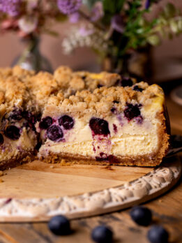 Side view of a slice of blueberry crumble cheesecake.