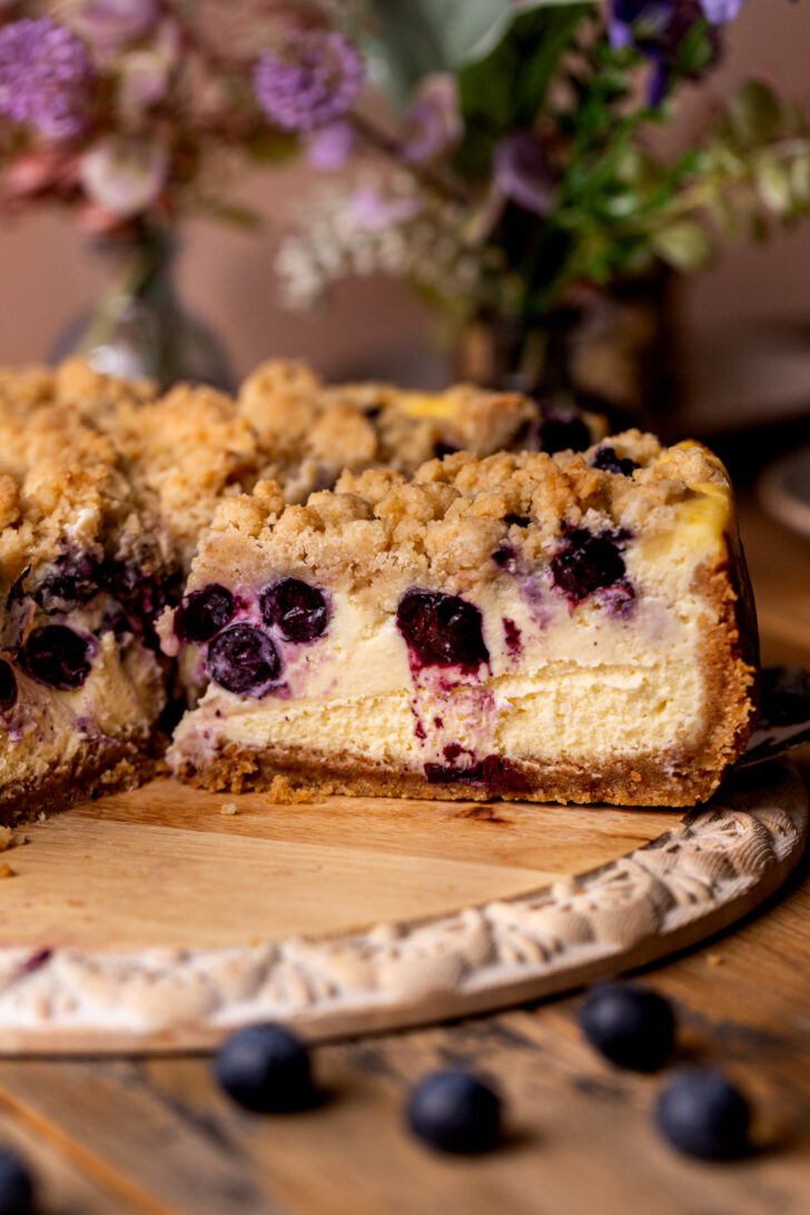 Side view of a slice of blueberry crumble cheesecake.