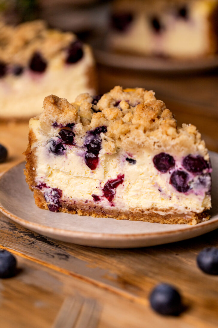 Side view of blueberry crumble cheesecake on a plate.