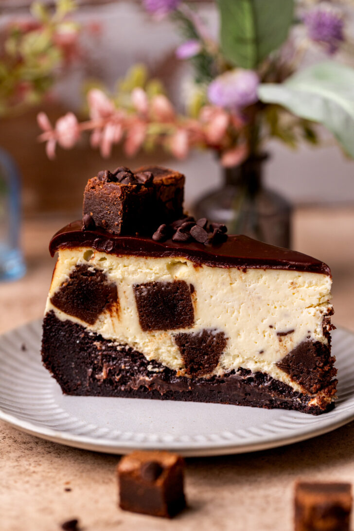 A slice of brownie filled cheesecake on a plate.