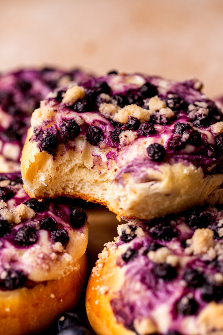 Bite missing from a blueberry cheesecake bun.
