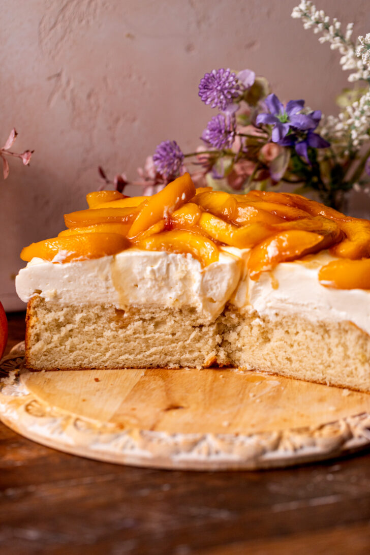 Cake split in half with peaches on top.