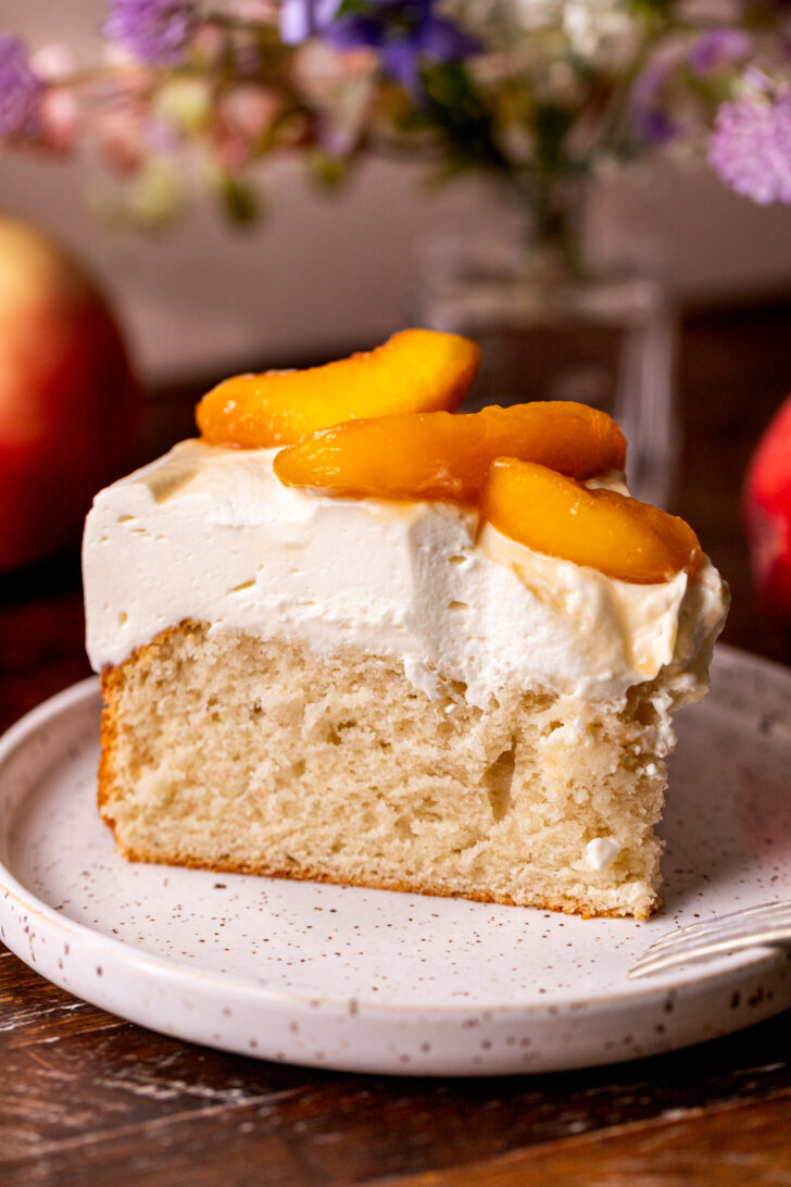 Slice of peaches and cream cake on a plate.