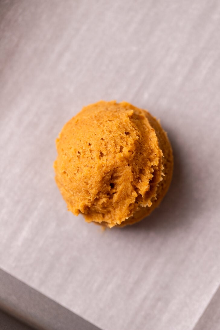 Pumpkin cookie dough ball on a cookie sheet.