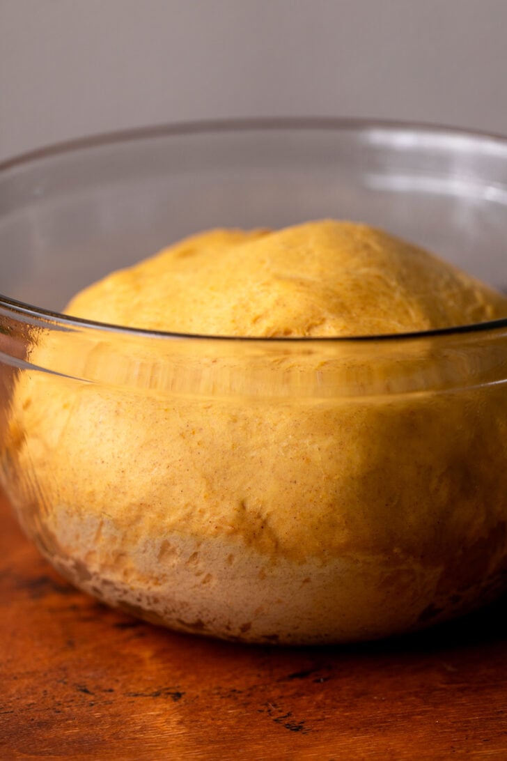 Risen pumpkin dough in a bowl.