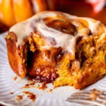 A pumpkin caramel cinnamon roll on a plate.