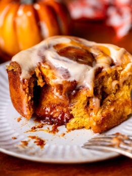 A pumpkin caramel cinnamon roll on a plate.