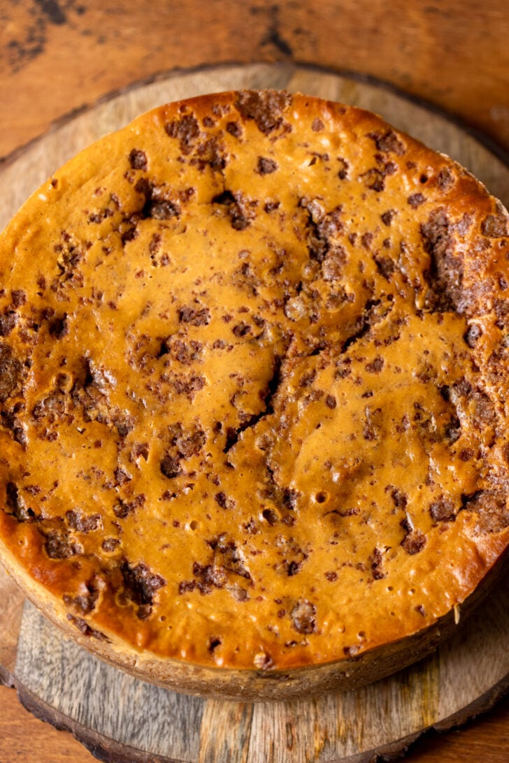 Baked cheesecake on a wood platter.