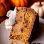 A slice of pumpkin cinnamon swirled cheesecake on it's side on a plate.