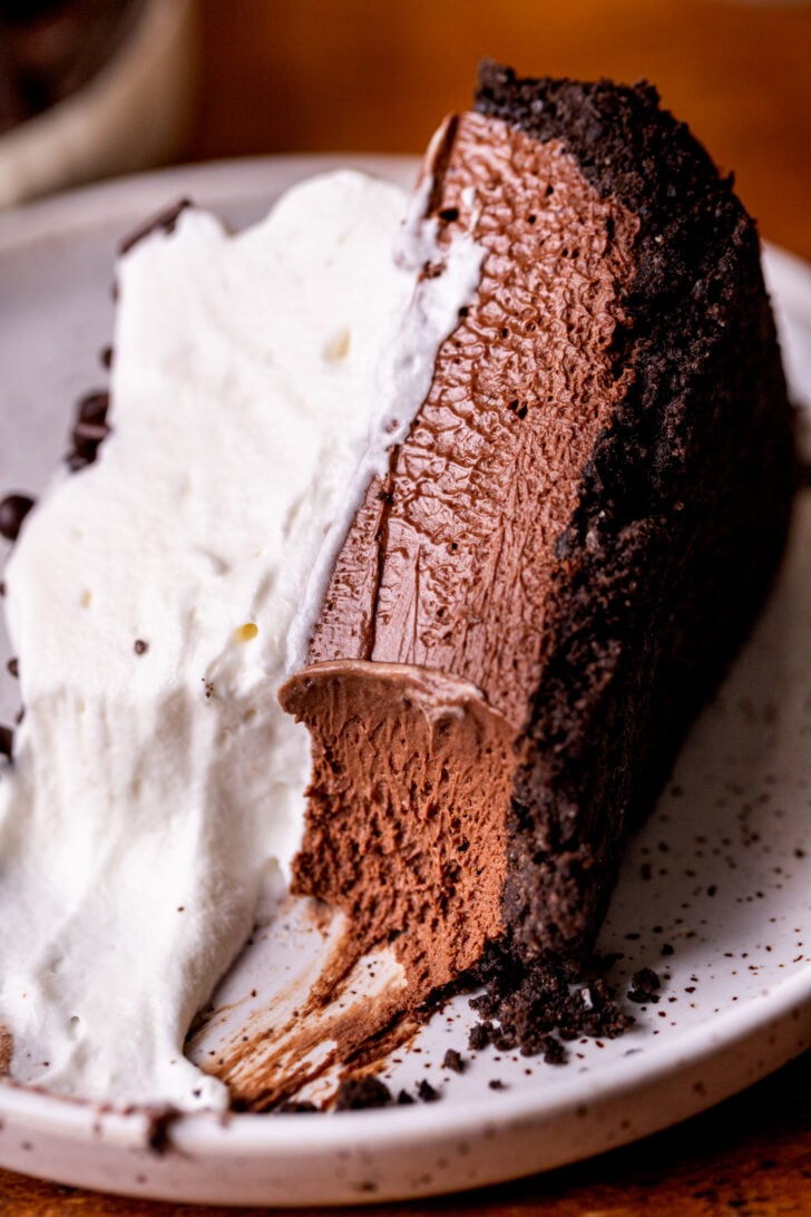 A bite missing from a piece of pie on a plate.