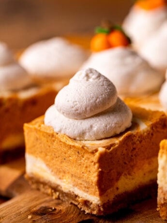 Whipped cream dollop on top of cheesecake bar.