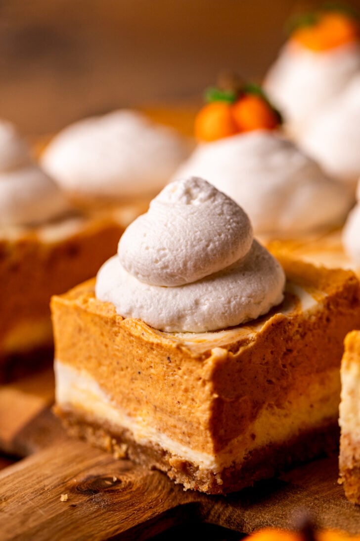 Whipped cream dollop on top of cheesecake bar.